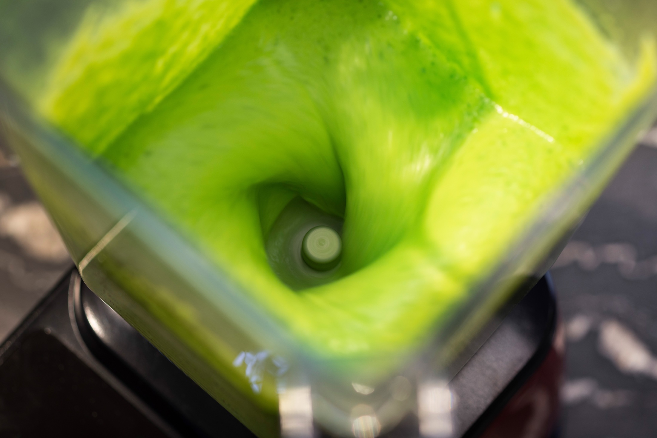 Dettaglio dall’alto del composto verde in movimento nel frullatore Blendtec