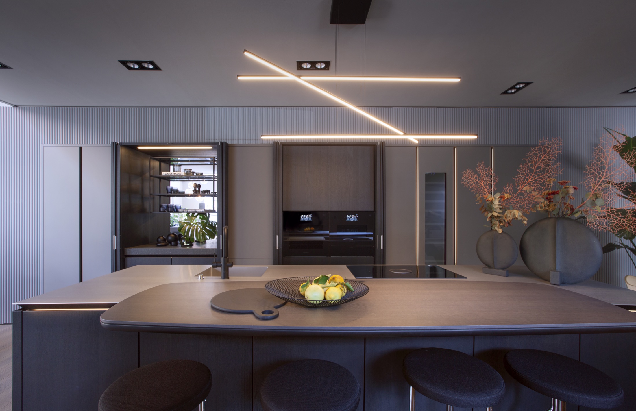 Cucina con grande isola, sgabelli e lampade lineari sospese