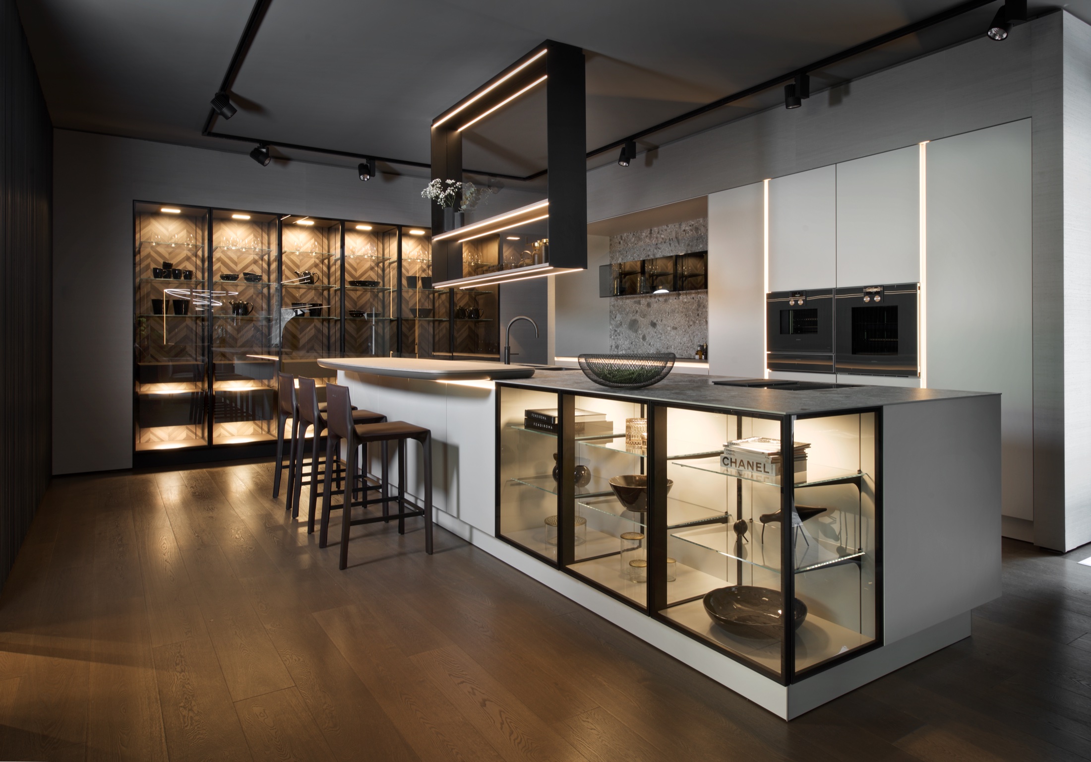 Cucina con isola, vetrine illuminate e colonne chiare