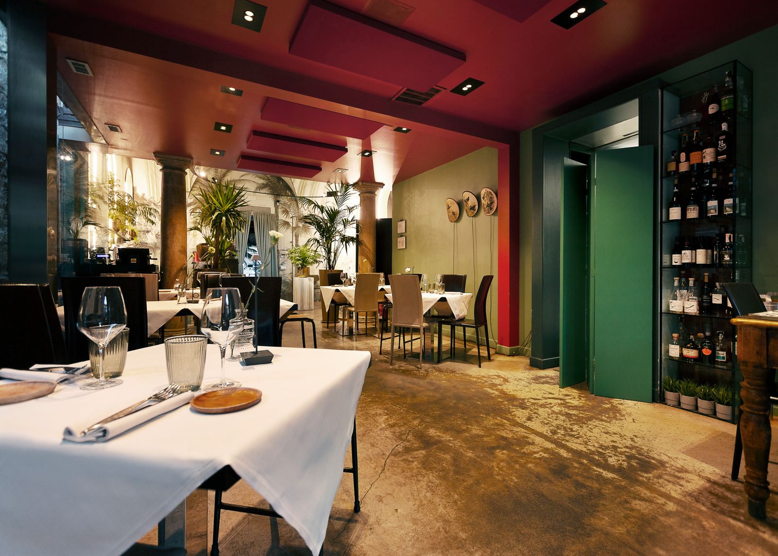 La sala del ristorante 19, tra tavoli apparecchiati, soffitto rosso e bottiglie